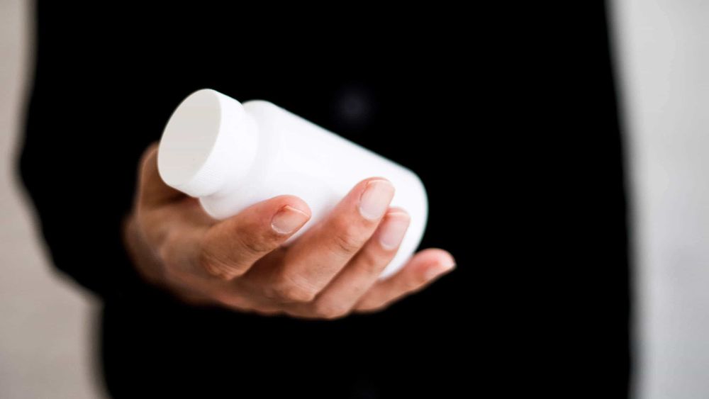 Person holding white pill bottle